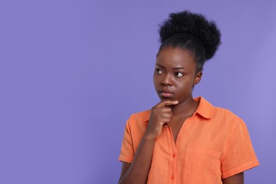 Photo of Portrait of thoughtful young woman on purple background. Space for text