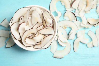 Tasty coconut chips on light blue wooden table, flat lay
