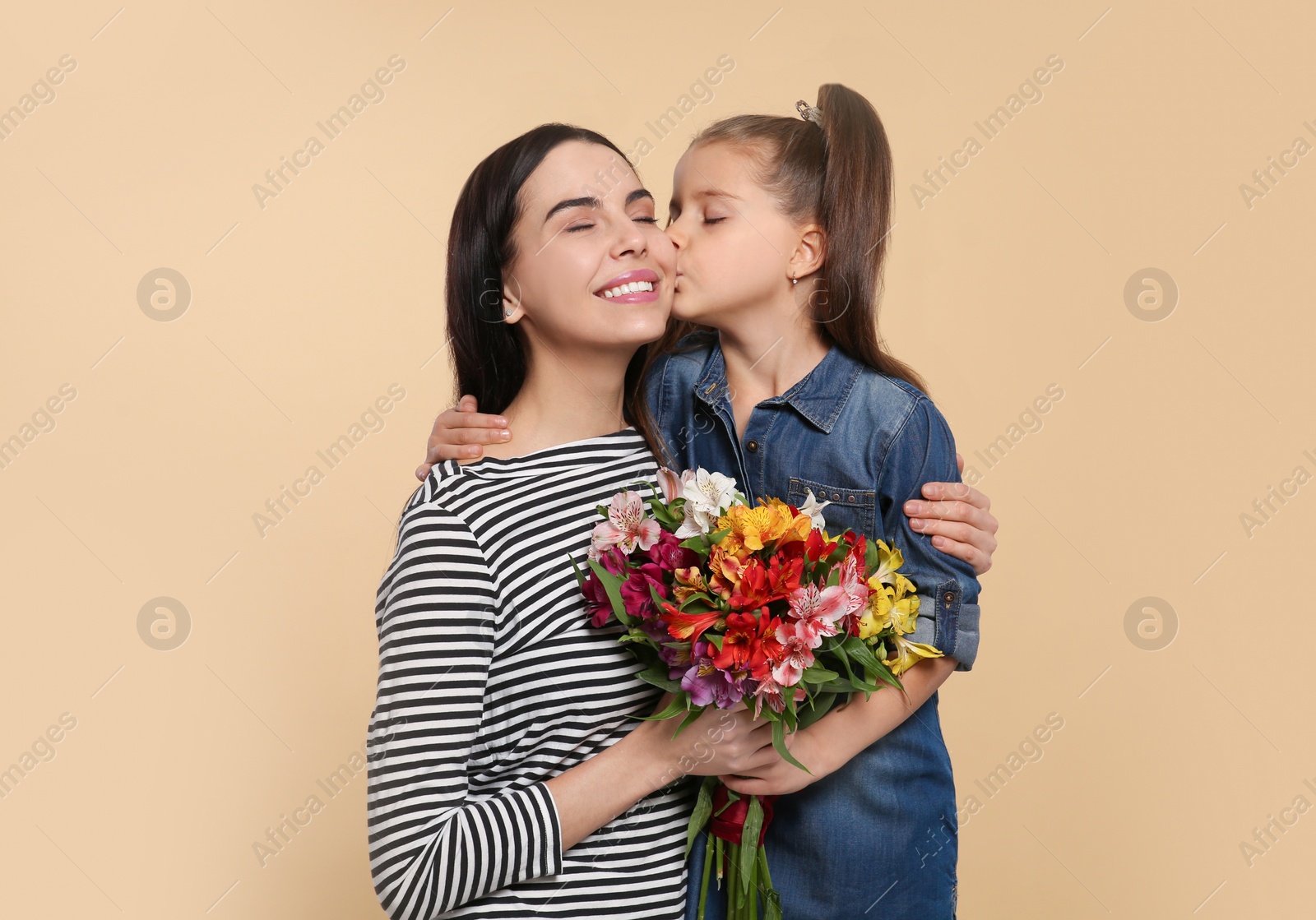 Photo of Happy woman with her cute daughter and bouquet of beautiful flowers on beige background, space for text. Mother's day celebration