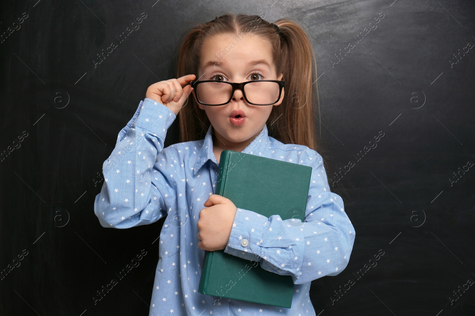 Photo of Cute little child wearing glasses near chalkboard. First time at school