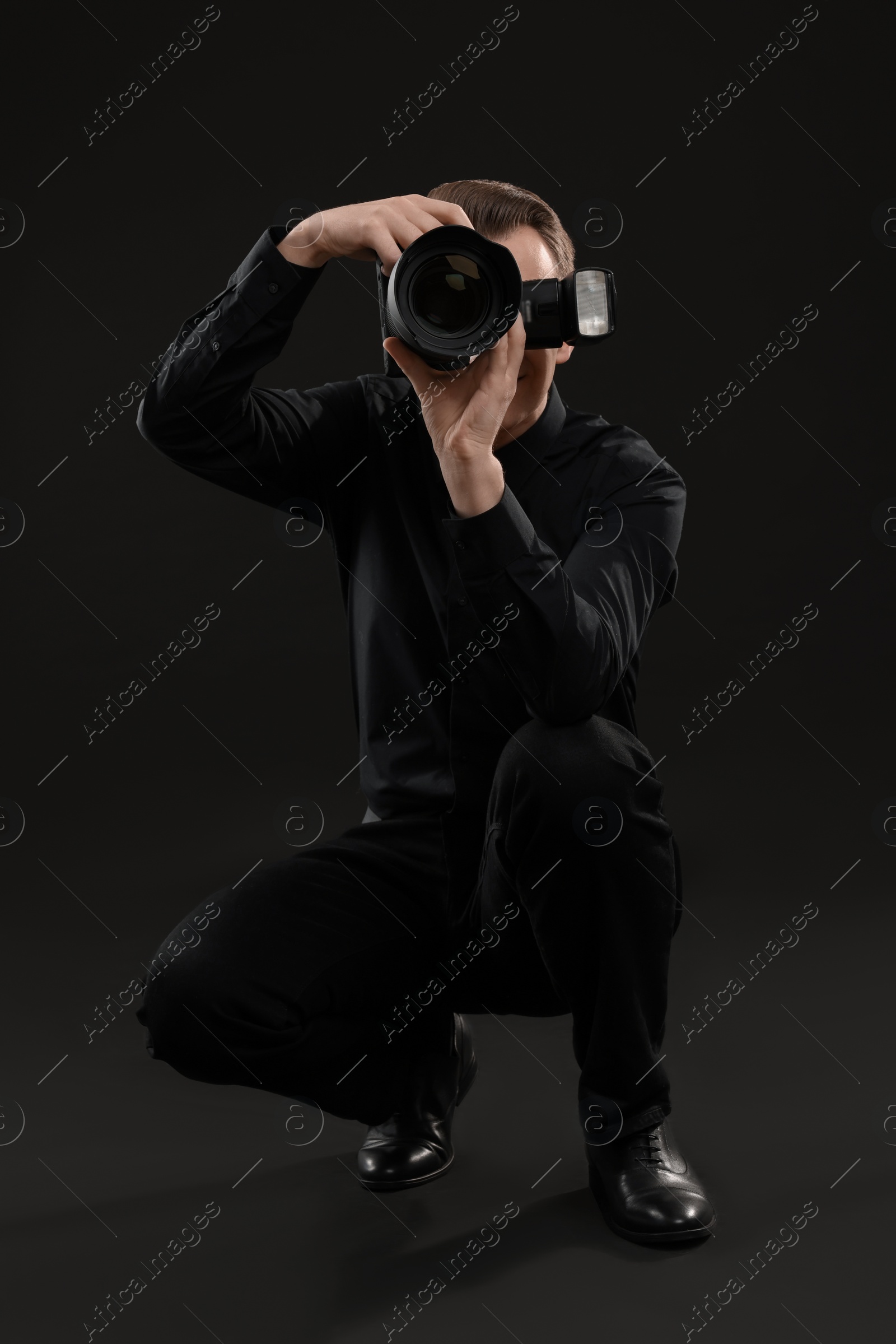 Photo of Professional photographer taking picture on black background