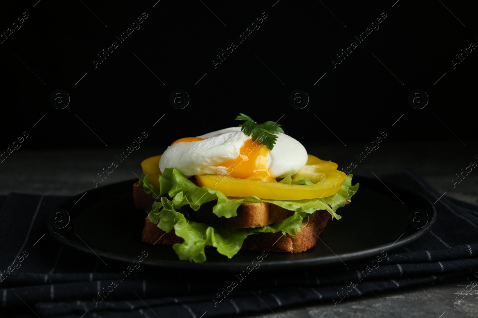 Photo of Delicious poached egg sandwich served on black plate