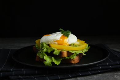 Photo of Delicious poached egg sandwich served on black plate