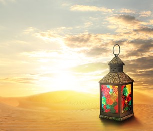 Image of Beautiful Arabic lantern on sand at sunrise, space for text