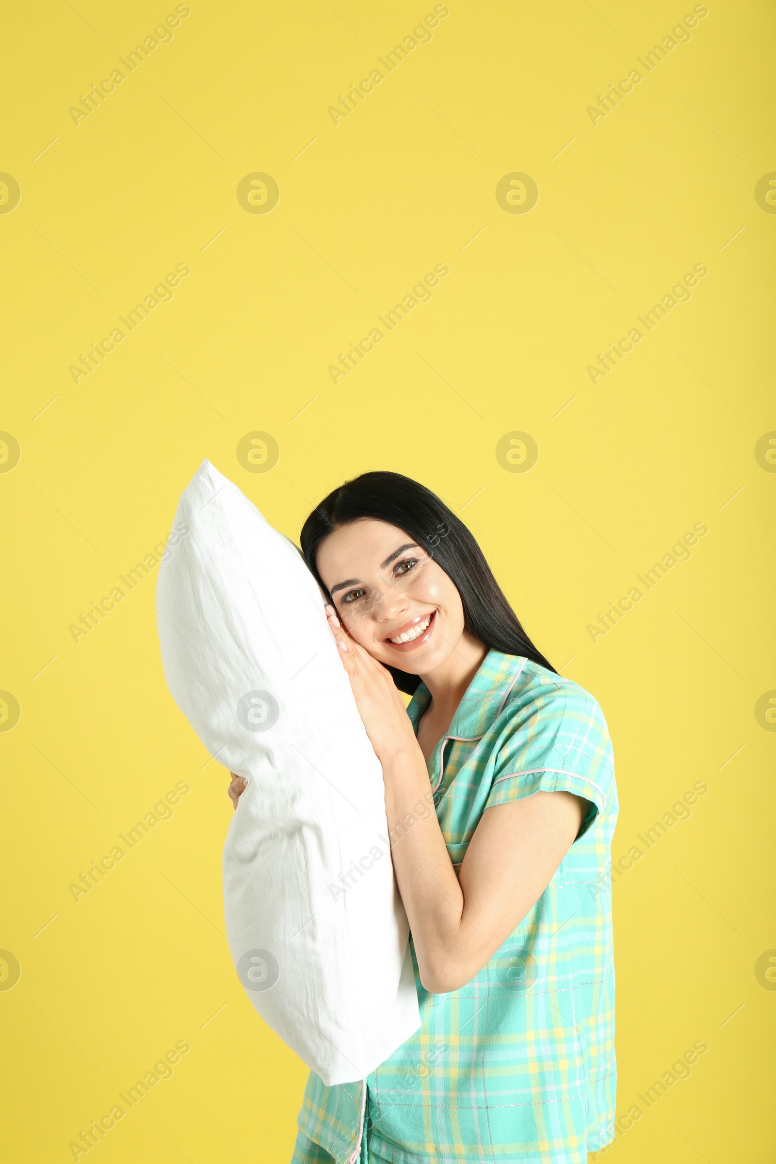 Photo of Young woman with pillow on yellow background