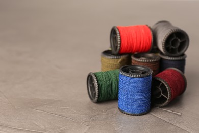 Set of color sewing threads on grey table, space for text