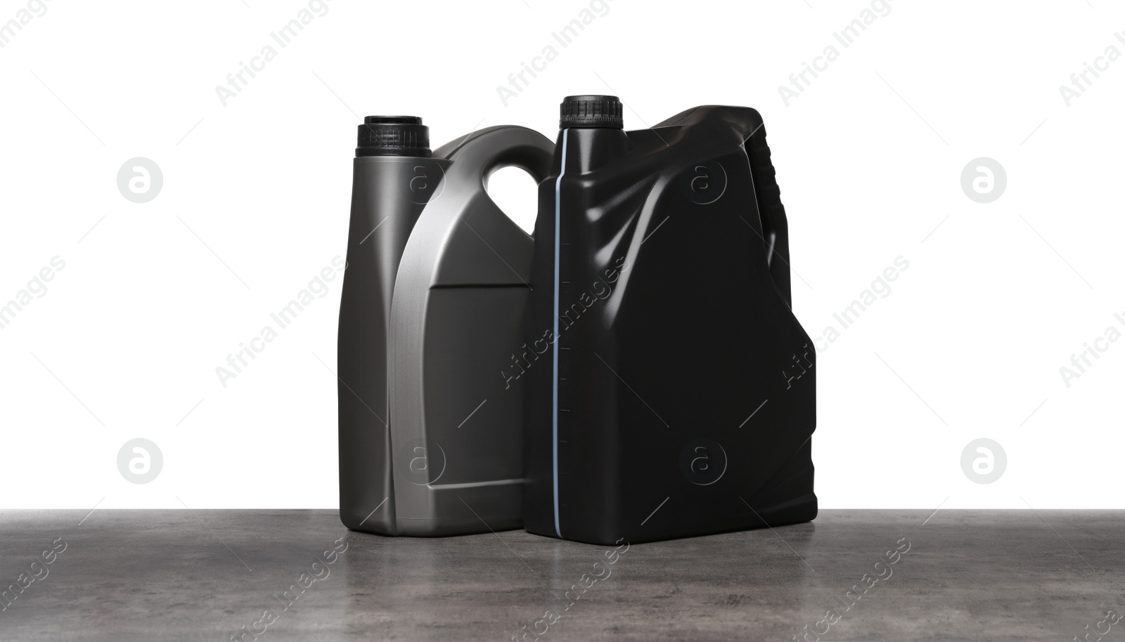 Photo of Motor oil in different containers on grey table against white background