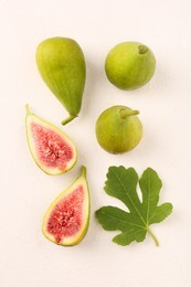 Photo of Cut and whole green figs with leaf on light table, flat lay