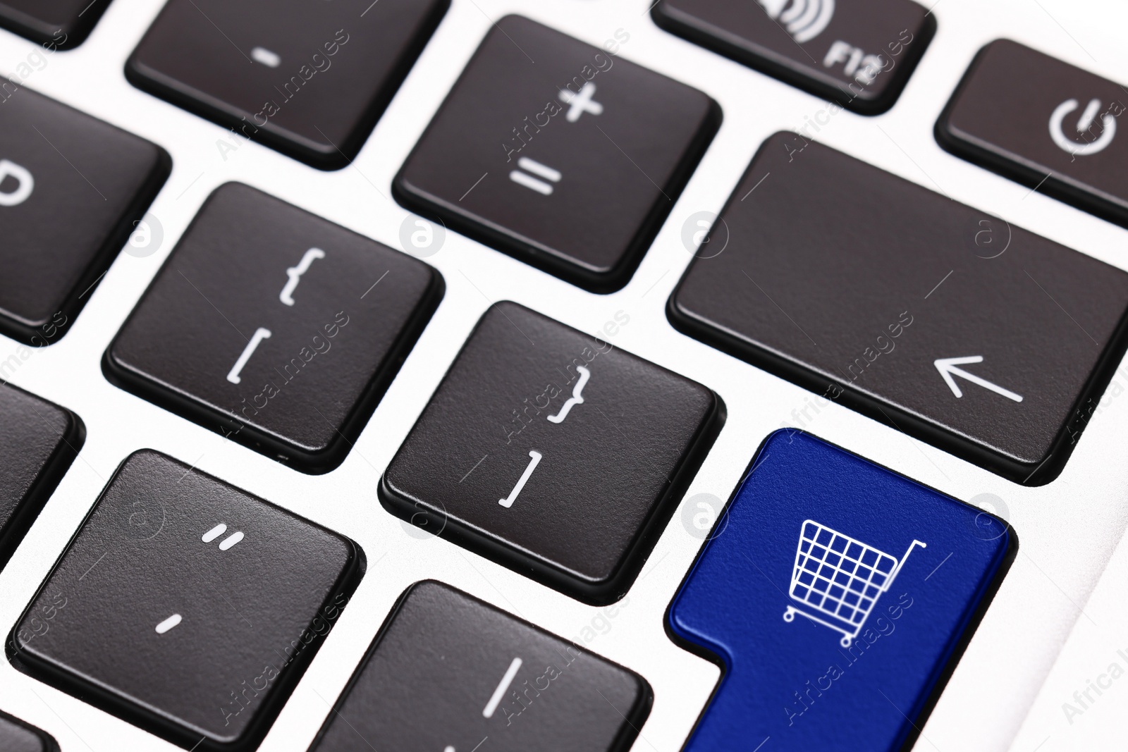 Image of Internet store. Blue button with shopping cart on computer keyboard, closeup