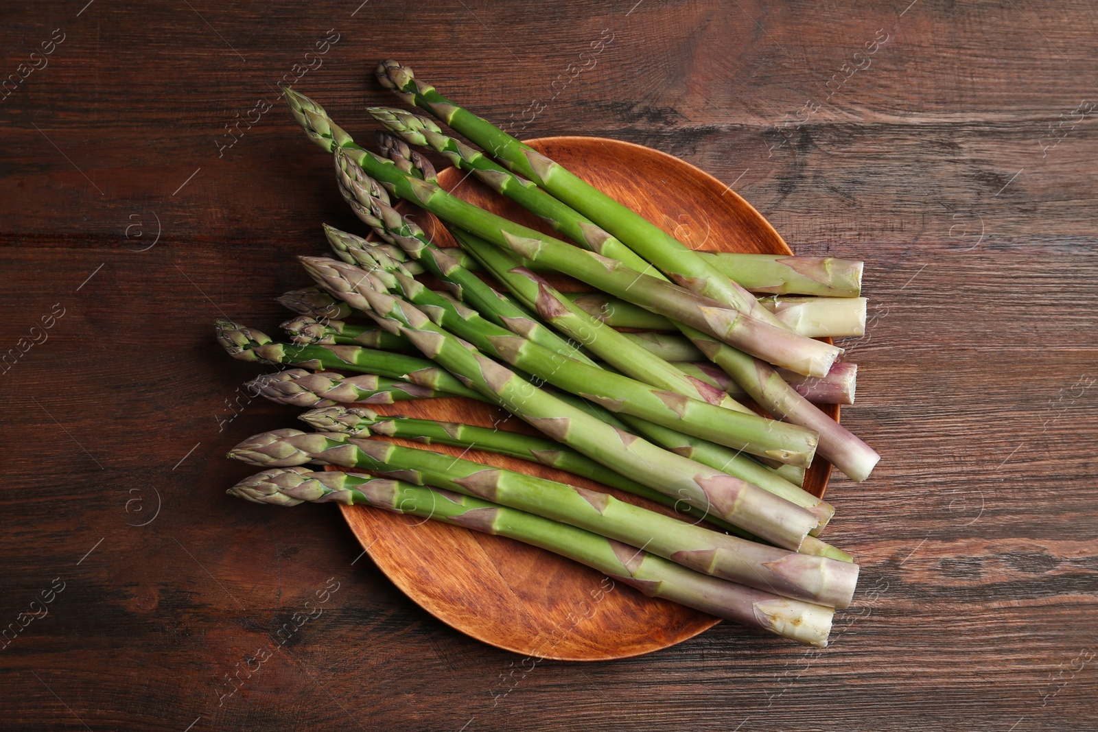 Photo of Fresh raw asparagus on wooden table, top view
