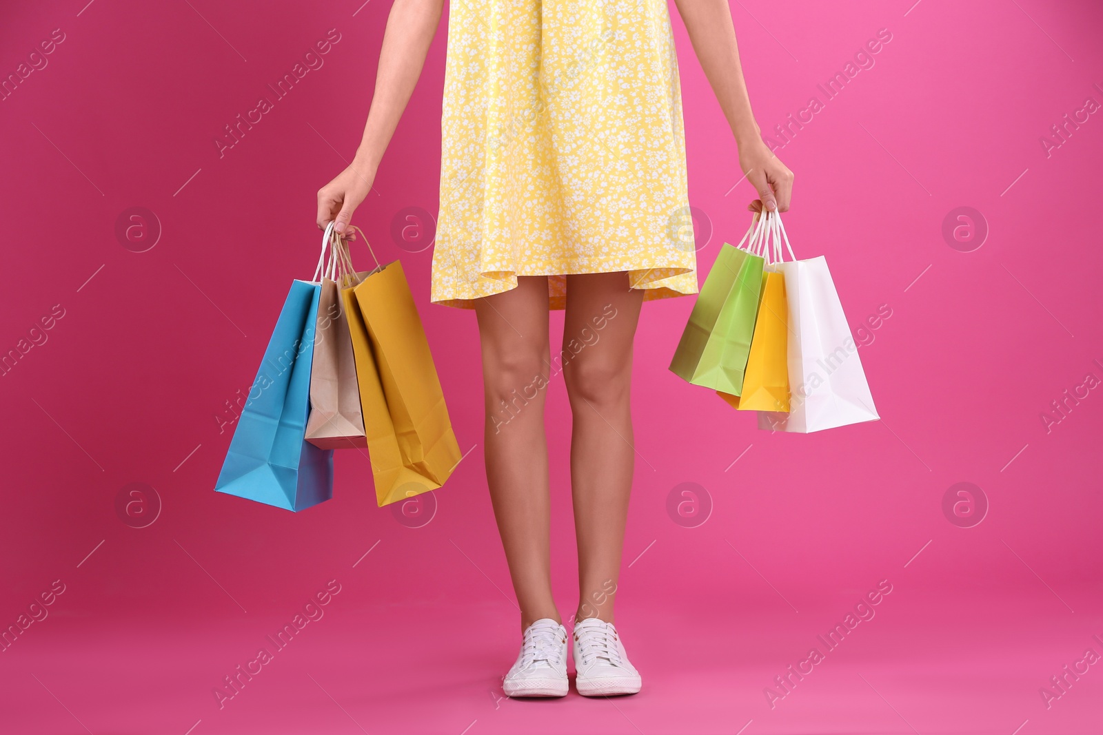 Photo of Young woman with shopping bags on color background, closeup