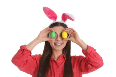 Photo of Beautiful woman in bunny ears headband  holding Easter eggs near eyes on white background