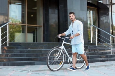 Handsome young hipster man with bicycle outdoors