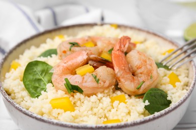 Photo of Tasty couscous with shrimps, bell pepper and basil on white table, closeup