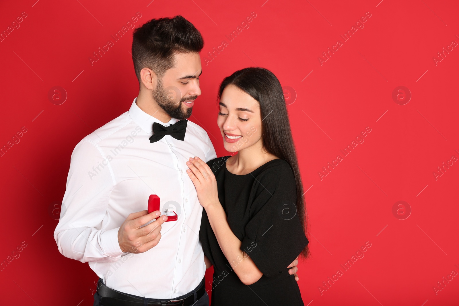 Photo of Man with engagement ring making marriage proposal to girlfriend on red background