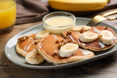 Photo of Tasty pancakes with sliced banana served on wooden table, closeup