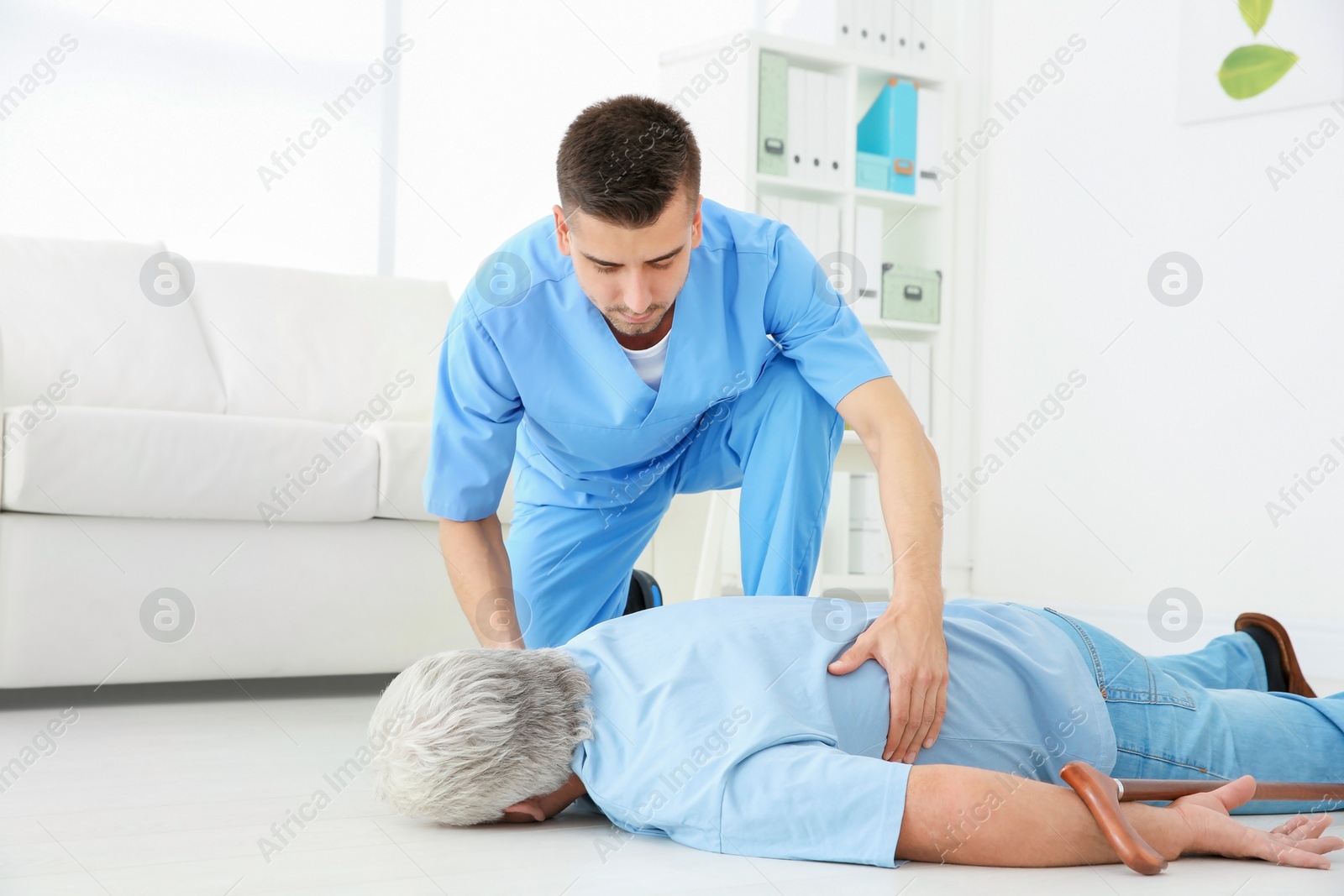 Photo of Young doctor giving first aid to senior man with heart attack in clinic