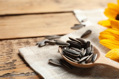 Photo of Raw sunflower seeds on wooden table, closeup. Space for text