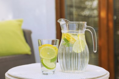 Photo of Water with lemons and limes on white table outdoors