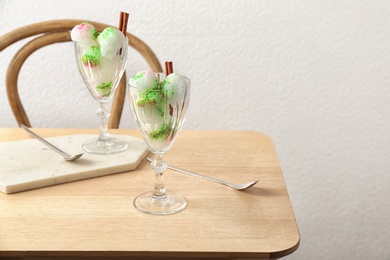 Photo of Glasses with snow ice cream dessert on table against light wall. Space for text