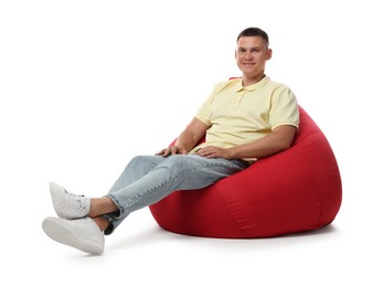 Handsome man sitting on red bean bag chair against white background