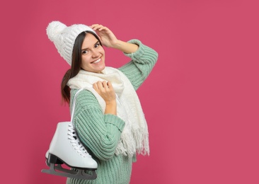 Photo of Happy woman with ice skates on pink background. Space for text