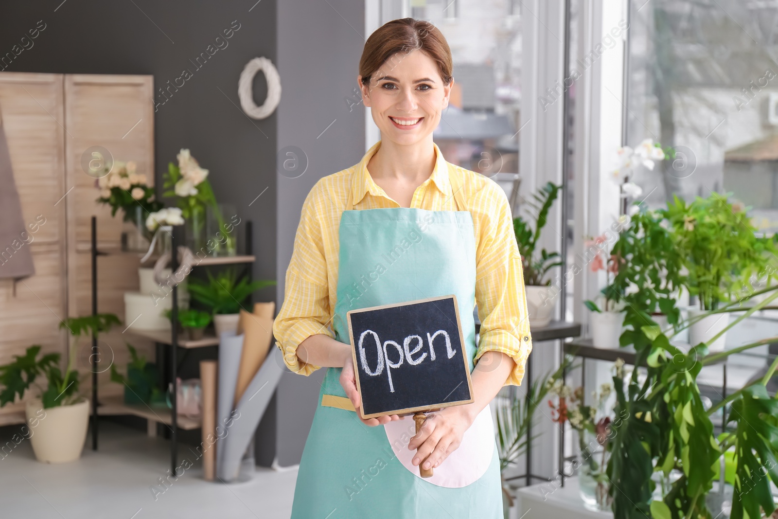 Photo of Female florist holding OPEN sign at workplace