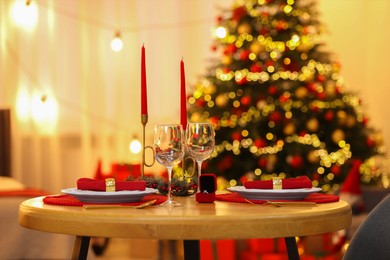 Photo of Making proposal. Christmas table setting with candles and engagement ring indoors