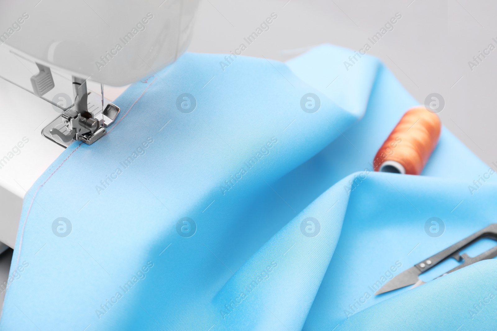 Photo of Sewing machine with fabric on table in tailor workshop, closeup