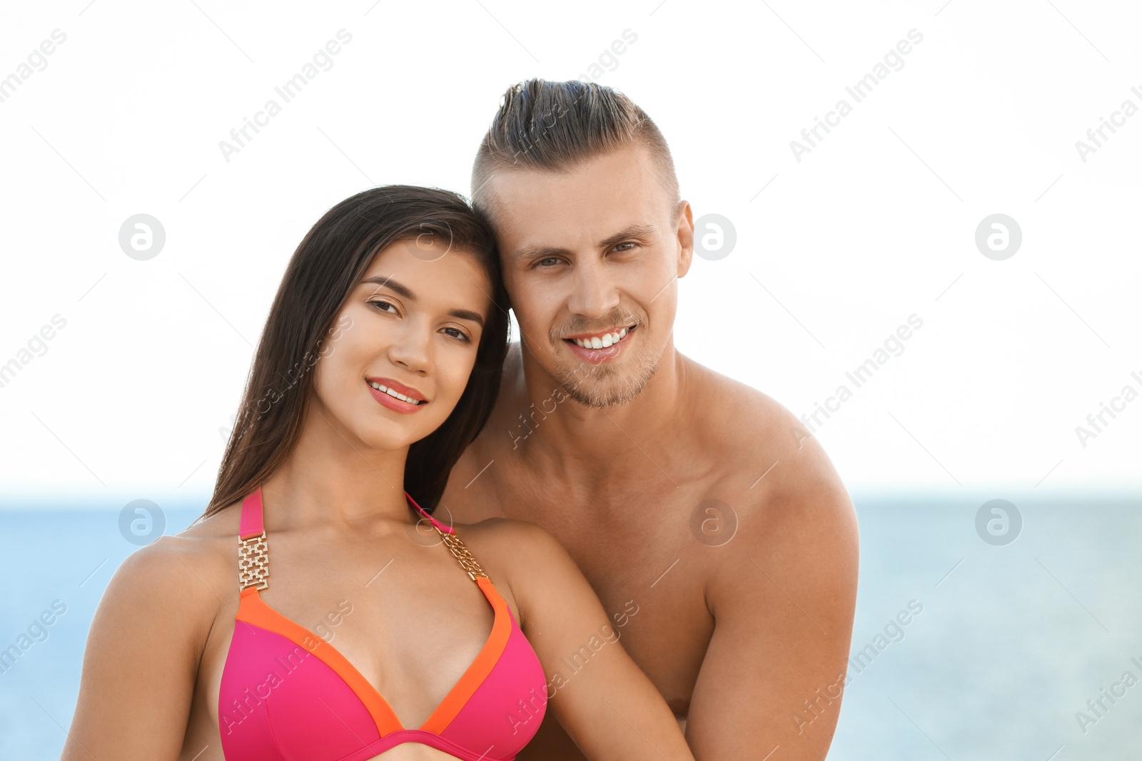 Photo of Young woman in bikini spending time with her boyfriend on beach. Lovely couple