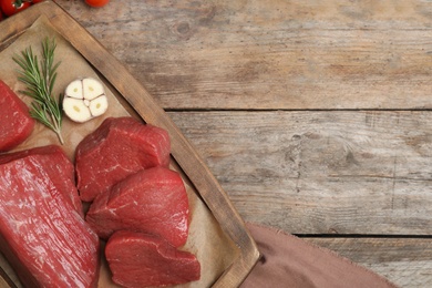 Photo of Flat lay composition with fresh raw meat, products and space for text on wooden background