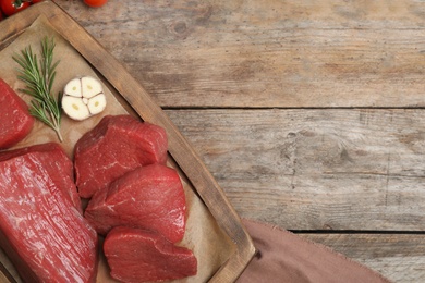 Flat lay composition with fresh raw meat, products and space for text on wooden background