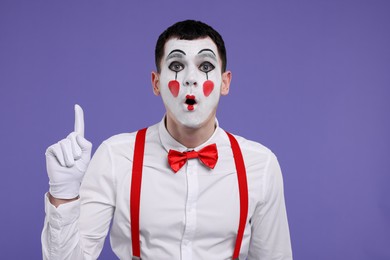 Photo of Funny mime artist gesturing on purple background