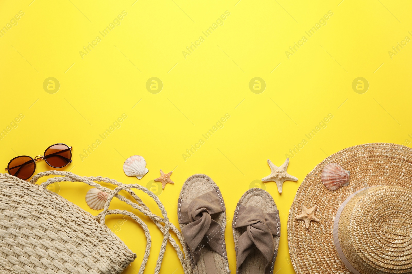 Photo of Stylish bag with beach accessories on yellow background, flat lay. Space for text