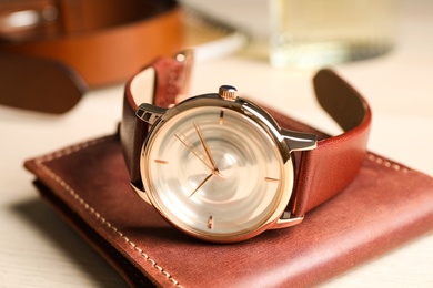 Photo of Luxury wrist watch and wallet on table, closeup