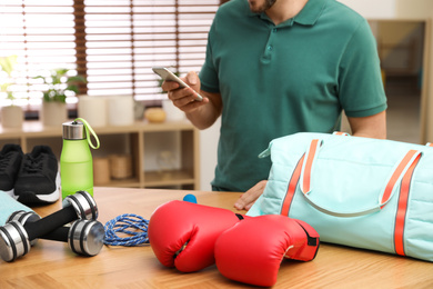 Photo of Man packing sports bag for training indoors, closeup