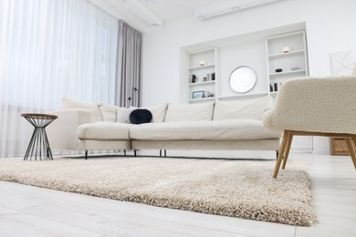 Fluffy carpet and stylish furniture on floor indoors, low angle view