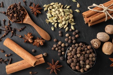Photo of Different spices on black textured table, flat lay