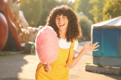 Portrait of happy woman with cotton candy outdoors on sunny day