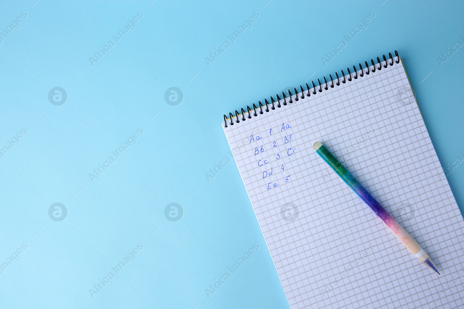 Photo of Letters and numbers written in notepad with erasable pen on light blue background, top view. Space for text