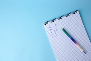 Letters and numbers written in notepad with erasable pen on light blue background, top view. Space for text