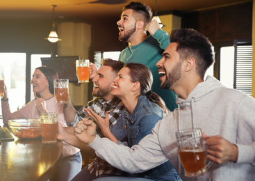 Photo of Group of friends watching football in sport bar