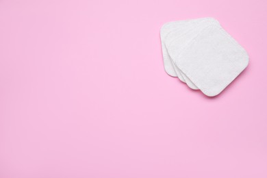 Photo of Clean cotton pads on pink background, flat lay. Space for text