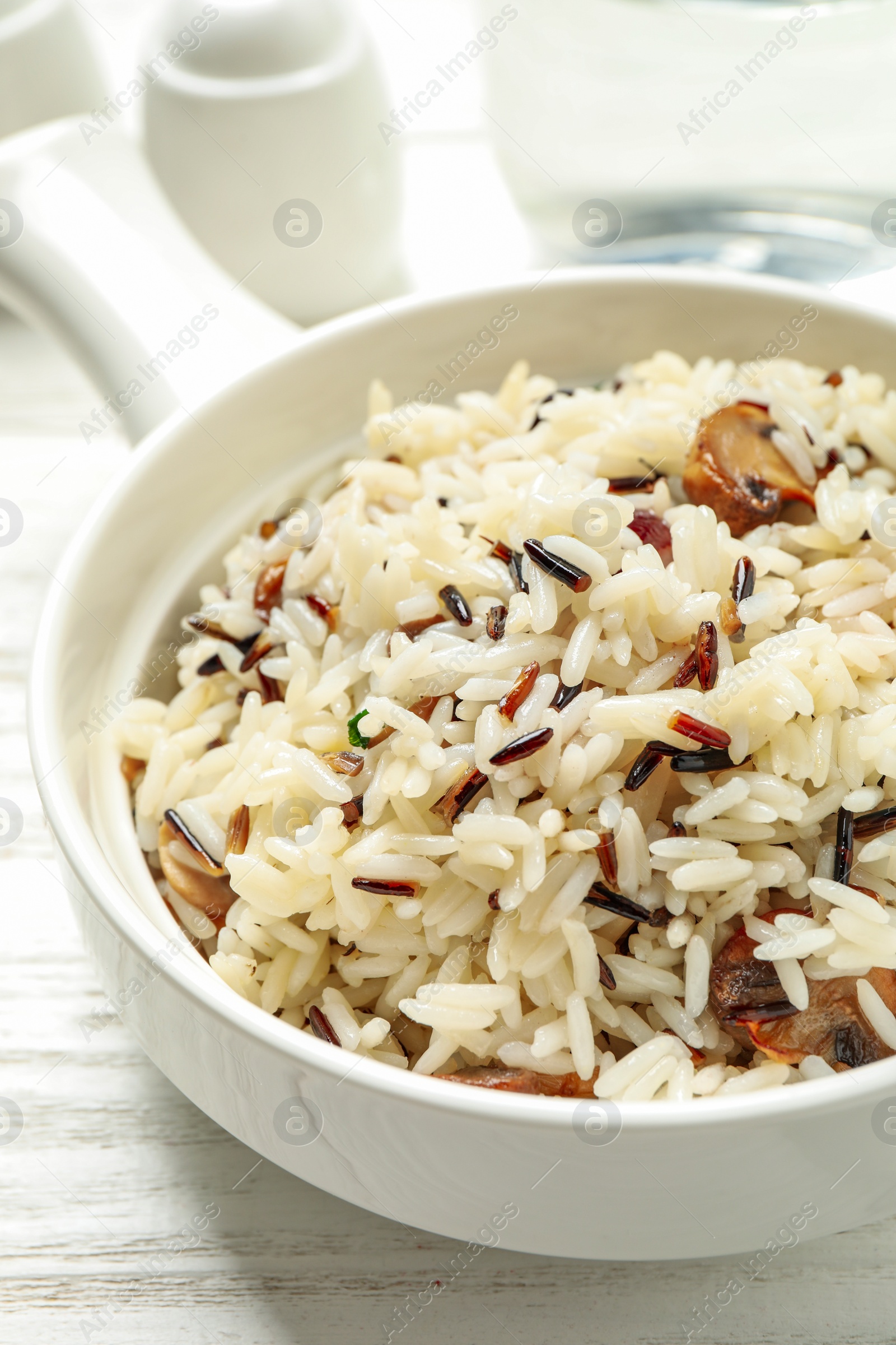 Photo of Delicious rice pilaf with mushrooms on white wooden table, closeup