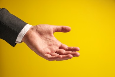 Man holding something in hand on yellow background, closeup