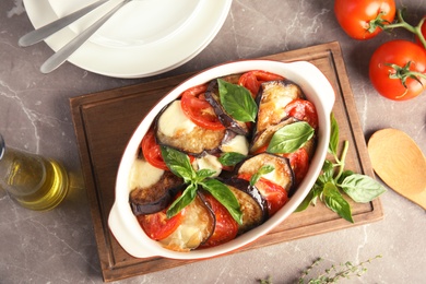 Photo of Flat lay composition with baked eggplant, tomatoes and basil in dishware on table