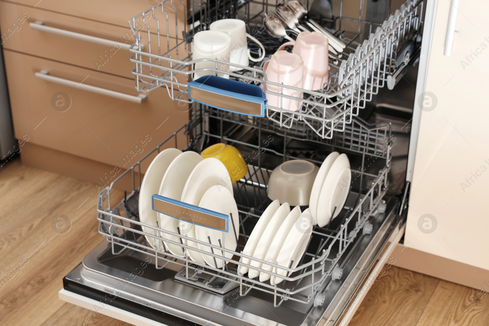 Photo of Open dishwasher with clean tableware in kitchen