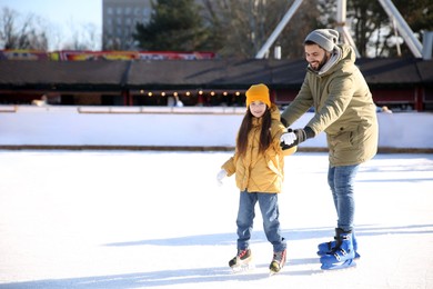 Father and daughter spending time together at outdoor ice skating rink