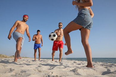 Group of friends playing football on beach