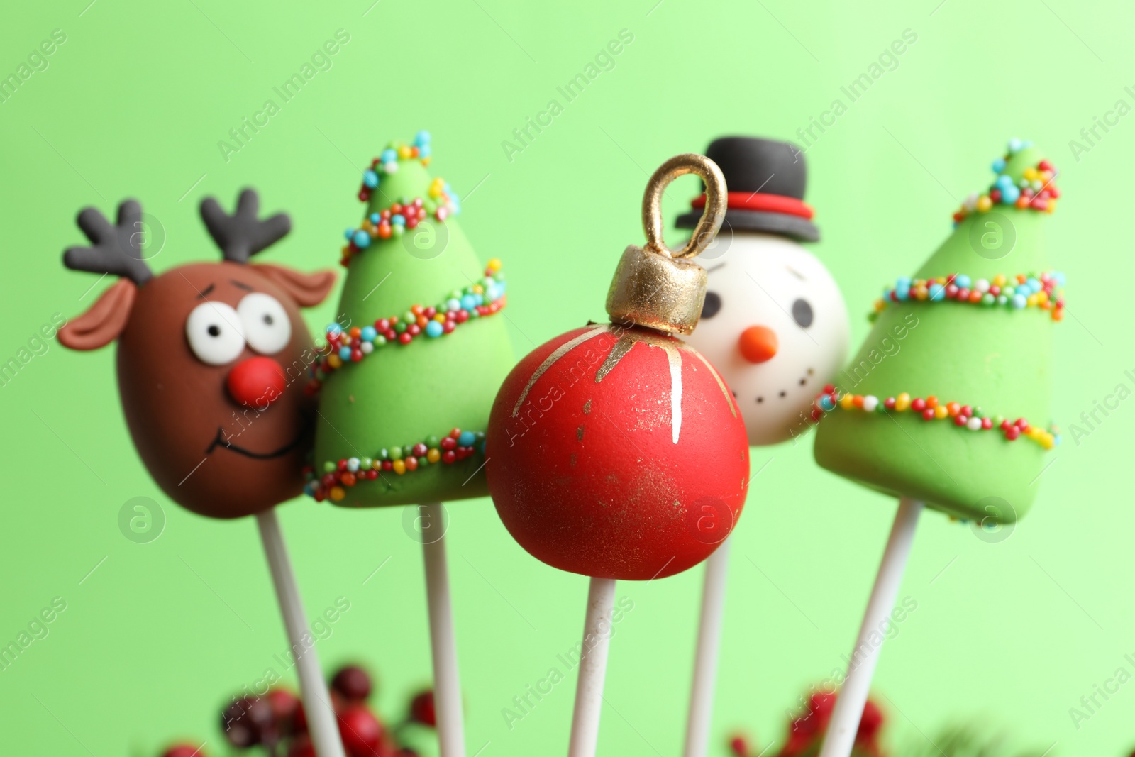 Photo of Delicious Christmas themed cake pops on green background, closeup